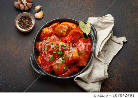 Raw uncooked chopped pieces of meat marinated with seasonings and parsley in black casserole dish top view on dark rustic background. Cooking ragout stew with marinated meat fillet pieces Raw uncooked chopped pieces of meat marinated with seasonings and parsley in black casserole dish top view on dark rustic background. Cooking ragout stew with marinated meat fillet pieces 107042491