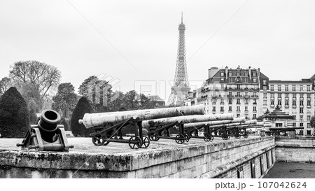 Historical cannons at Les Invalides and parisian cityscape with Eiffel Tower, Paris, France. Black and white photography. Black and white photography. 107042624