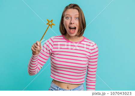 Magician witch young woman gesturing with magic wand making wish come true, casting magician spell 107043023