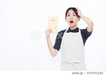 白い背景の前で給料袋を持って頭を抱える30代の主婦 白い背景の前で給料袋を持って頭を抱える30代の主婦 107043292