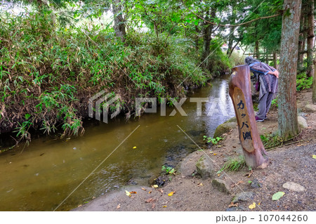 カッパ淵でのぞき込む女性 107044260
