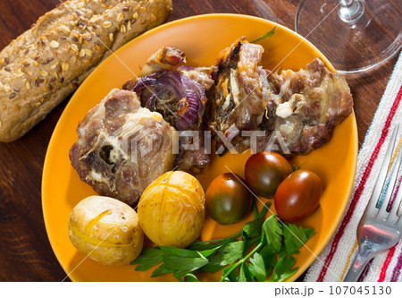 Lamb leg chops with baked potatoes, tomatoes and greens Lamb leg chops with baked potatoes, tomatoes and greens 107045130