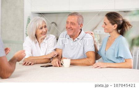 Married couple and senior parents talk about home life 107045421