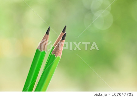 three sharp green wooden pencil on blur nature background with bokeh 107047705
