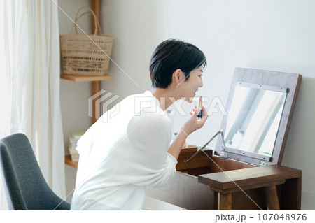 部屋でメイクをする女性 部屋でメイクをする女性 107048976