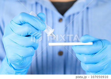 The doctor holds a COVID-19 swab collection, wears blue gloves and a PPE protective mask, and carries a test tube to collect the OP NP and test coronavirus. 107050910