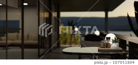 A relaxation area with a table on a modern and spacious balcony in the evening. A relaxation area with a table on a modern and spacious balcony in the evening. 107051804