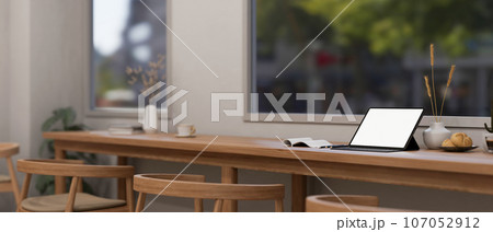 A digital tablet mockup on a wooden table against the window in a cozy minimalist coffee shop. 107052912