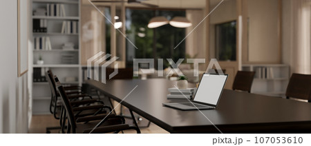 A laptop mockup on a modern, dark meeting table in a modern, spacious meeting room. A laptop mockup on a modern, dark meeting table in a modern, spacious meeting room. 107053610
