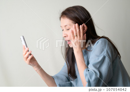 スマホを操作して考え中のシニア女性 スマホを操作して考え中のシニア女性 107054042
