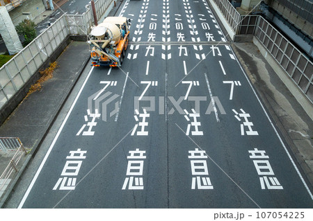 急カーブ注意の路面表示とミキサー車 107054225