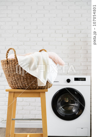 Laundry room with washing machine and basket with laundry 107054801