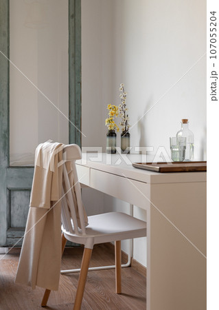 Vertical shot chair stands behind a table in a living room for single travelers with decor and water. High class service hotel concept. Copyspace Vertical shot chair stands behind a table in a living room for single travelers with decor and water. High class service hotel concept. Copyspace 107055204