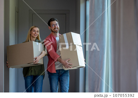 Young couple carrying cardboards with clothes while relocation Young couple carrying cardboards with clothes while relocation 107055392