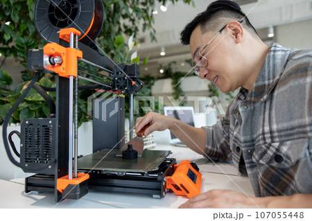 Asian designer engineer using 3D printer in laboratory and studying product prototype. Asian designer engineer using 3D printer in laboratory and studying product prototype. 107055448