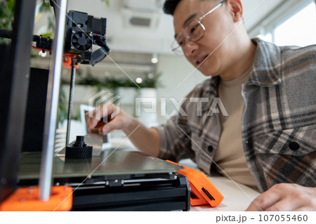 Asian designer engineer using 3D printer in laboratory and studying product prototype. Asian designer engineer using 3D printer in laboratory and studying product prototype. 107055460