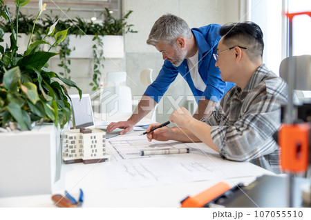 Men working with 3D printer and blueprint for designing mechanical parts in high tech workshop. Men working with 3D printer and blueprint for designing mechanical parts in high tech workshop. 107055510