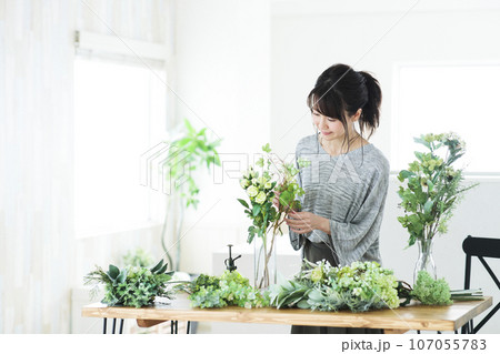 リビングでフラワーアレンジメントをする若い女性 107055783