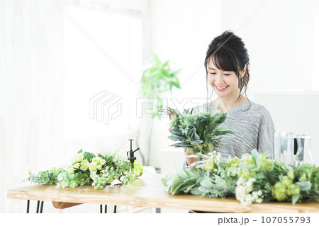 リビングでフラワーアレンジメントをする若い女性 107055793