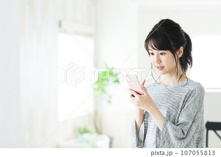 リビングでスマホを操作する若い女性 107055813