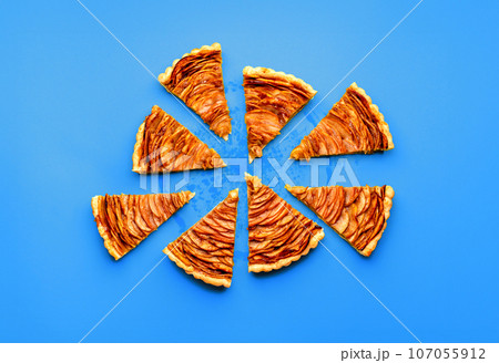 Sliced apple pie minimalist on a blue table, above view 107055912
