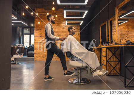 Man getting new trendy haircut or hairstyle with professional male barber. 107056030