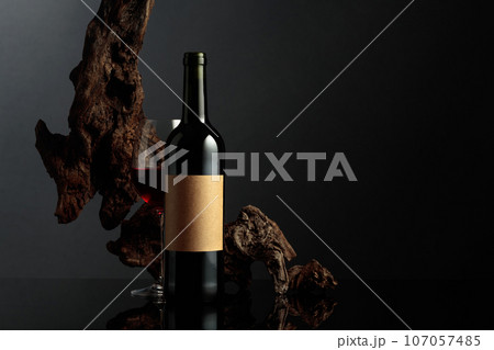 Red wine and old weathered snag on a black background. 107057485