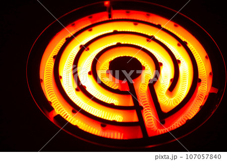 徐々に黄色から赤く明るく発熱するコイル状の電熱線（ニクロム線）黒背景にレトロな電気コンロの黒背景写真 107057840