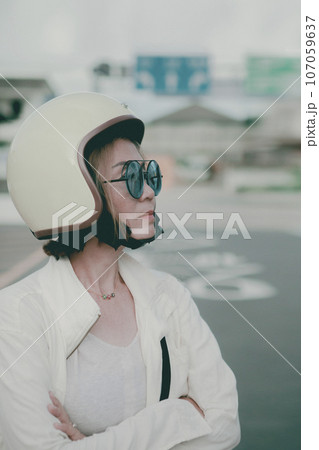 asian woman wearing anti-knock helmet standing on city road side 107059637