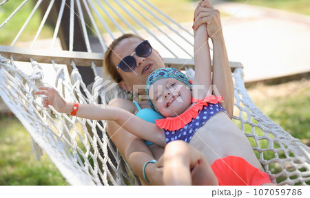 Woman with child swing on hammock in street Woman with child swing on hammock in street 107059786