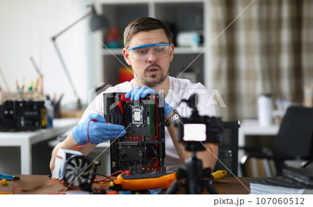 Gloved craftsman holds disassembled computer equipment and shows it to comer Gloved craftsman holds disassembled computer equipment and shows it to comer 107060512