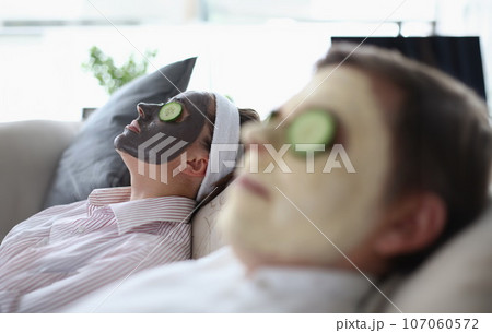 Man and a woman are lying on couch with rejuvenating mask on their face 107060572