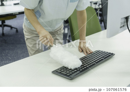 キーボードの埃を取る女性清掃員の手元 107061576