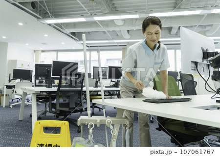 オフィスでキーボードの埃を取る女性清掃員 オフィスでキーボードの埃を取る女性清掃員 107061767