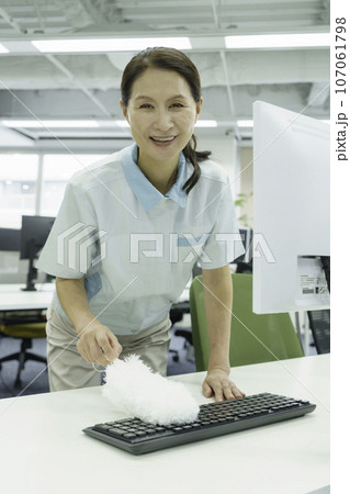 オフィスでキーボードの埃を取る女性清掃員 縦位置 オフィスでキーボードの埃を取る女性清掃員 縦位置 107061798