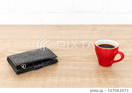 Cup of coffee with a wallet on the wooden table. Cup of coffee with a wallet on the wooden table. 107063073