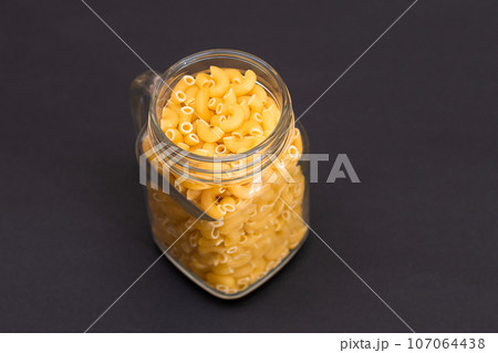 Uncooked Chifferi Rigati Pasta in Glass Jar on Black Background 107064438
