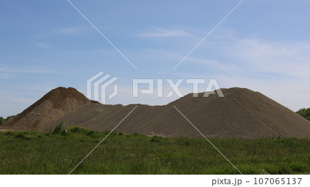hills of rounded stones at a gravel mining site, excavation of minerals and rock from the ground on an industrial scale, a pile of large cobblestones in the landscape hills of rounded stones at a gravel mining site, excavation of minerals and rock from the ground on an industrial scale, a pile of large cobblestones in the landscape 107065137