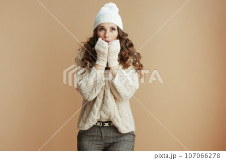 trendy woman against beige background warming hands trendy woman against beige background warming hands 107066278