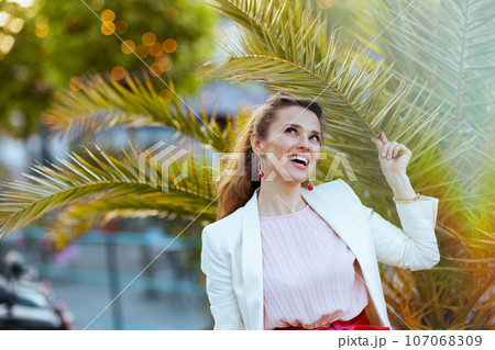 happy modern woman in pink dress and white jacket in city happy modern woman in pink dress and white jacket in city 107068309