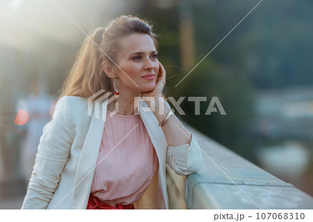 pensive stylish woman in pink dress and white jacket in city pensive stylish woman in pink dress and white jacket in city 107068310