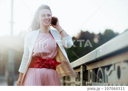 happy stylish woman in city speaking on smartphone 107068311