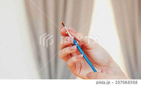 Artist brush. Painting tool. Unrecognizable woman hand with dirty wooden paintbrush bristle creative hobby in workshop studio. Artist brush. Painting tool. Unrecognizable woman hand with dirty wooden paintbrush bristle creative hobby in workshop studio. 107068508