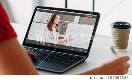 Video tutoring. Remote education. Woman student in online virtual class with female coach professional explaining lesson on laptop screen at home. Video tutoring. Remote education. Woman student in online virtual class with female coach professional explaining lesson on laptop screen at home. 107068585