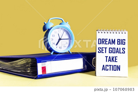 Dream Big - Set Goals - Take Action, handwriting in notebook with folder and clock  107068983