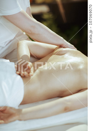 Closeup on massage therapist in spa salon massaging clients back Closeup on massage therapist in spa salon massaging clients back 107069070
