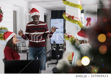 Diverse business team enjoying coffee break at work, having fun together in festive adorn office during holiday season. Colleagues feeling Christmas spirit mood, relaxing in xmas ornate workspace Diverse business team enjoying coffee break at work, having fun together in festive adorn office during holiday season. Colleagues feeling Christmas spirit mood, relaxing in xmas ornate workspace 107069423