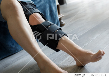 Patient wearing knee brace support after injury and surgery. Healthcare and medical concept. 107069504