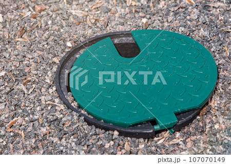 A plastic hatch in the garden covering the connection point for the irrigation hose. A protective hatch in the garden for connecting water and watering plants. 107070149