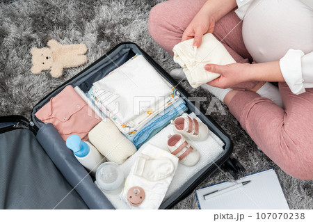 pregnant lady on the floor, deeply involved in packing her suitcase, mirroring the excitement of the future mother journey pregnant lady on the floor, deeply involved in packing her suitcase, mirroring the excitement of the future mother journey 107070238